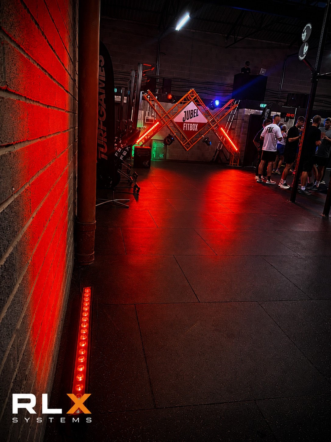 Venue corridor lit with red LED battens leading to a branded stage